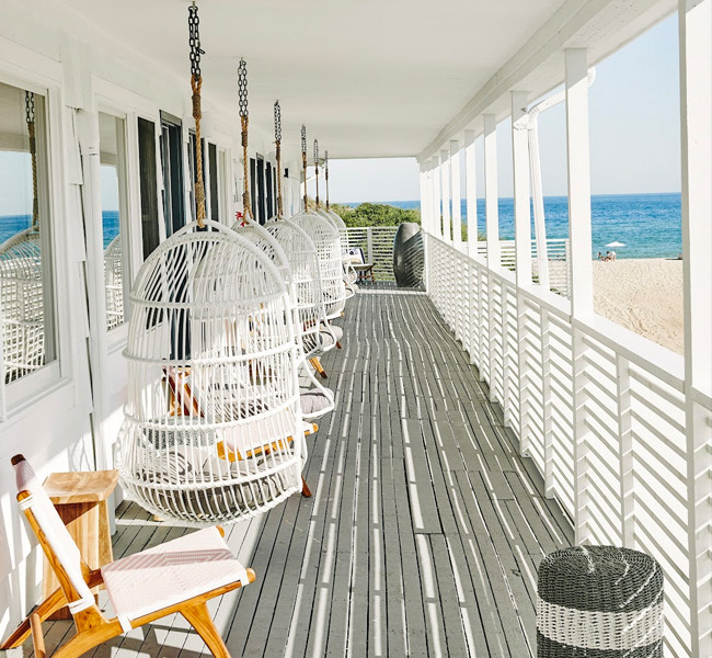 a spacious porch with several hanging chairs with a view of the ocean
