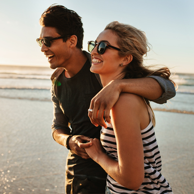 man and woman laughing and walking on the beach
