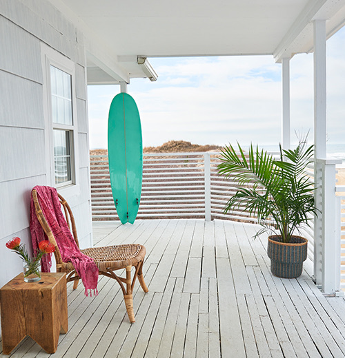 view of a teal surfboard and a brown chair on a porch