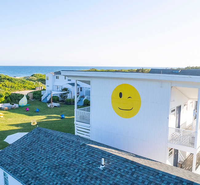 view of a building at hero beach club with a smiley face on the side with the ocean in the background
