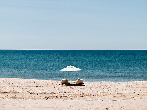 view of an umbrella and two beach seats at the shore