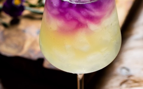 closeup image of a cocktail with purple on the top of the drink