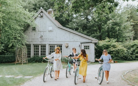 four women walking on the property outside with their beach cruiser bikes
