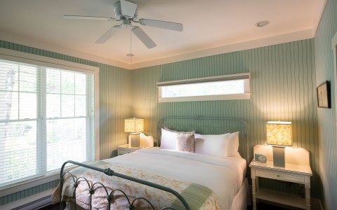 light green colored bedroom walls with a queen sized bed and two nightstands