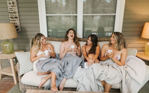group of women sitting on a bench outside their cottage laughing