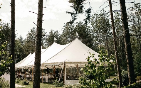 large combined tents set up outside amidst the trees for wedding reception 