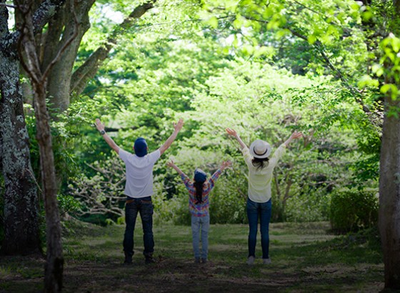 group of people standing in the forest with their hands in the air