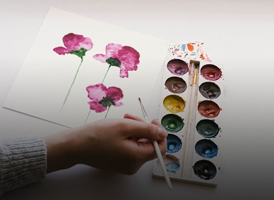 person using watercolors to paint flowers