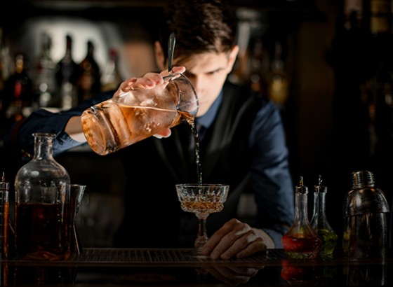 bartender pouring a drink into a glass