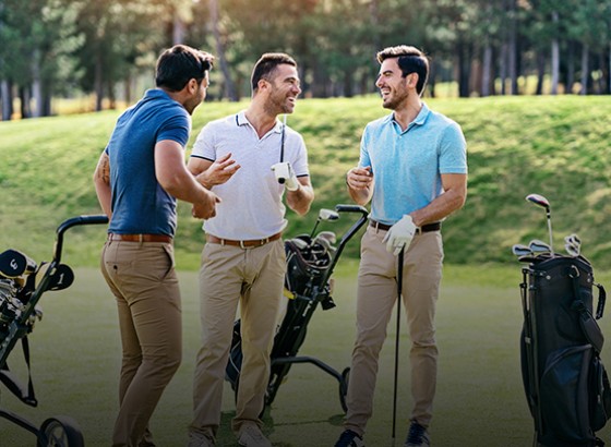 group of golfers standing outside by their golf bags laughing