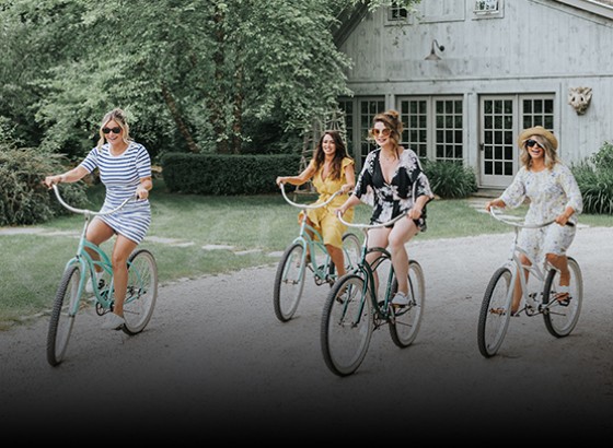four women riding on beach cruiser bikes on property 