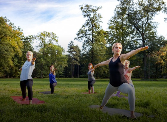 group of people doing yoga outside in warrior pose