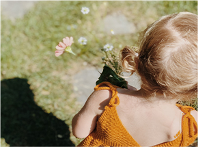 young girl holding flowers from garden outside