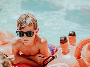 kid in sunglasses laying on a float in the pool