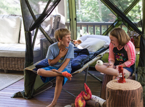 two kids laughing in a tent pitched on their porch