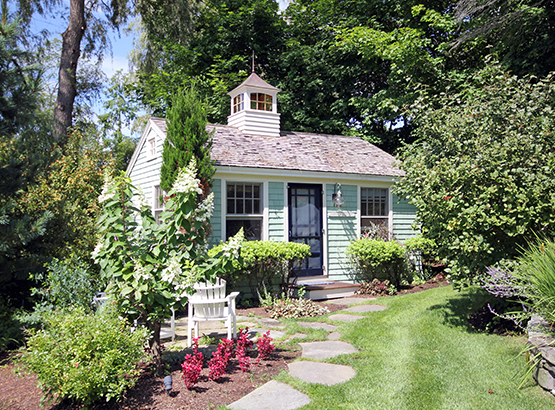exterior of a cottage surrounded by grass and a garden