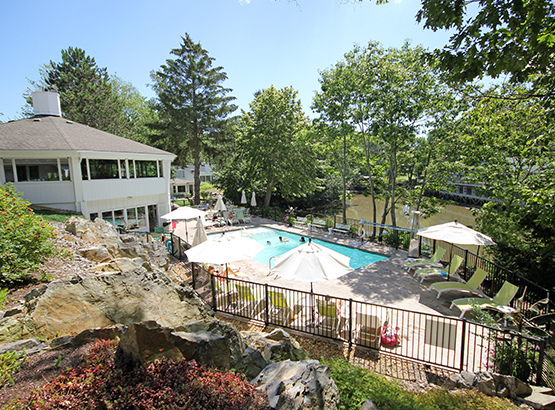 aerial image of hotel pool with lounge seating, trees, and the building to the right