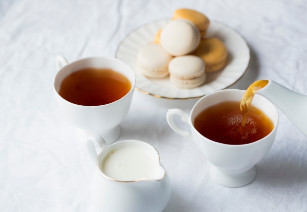 macaroons on a plate next to cups of tea