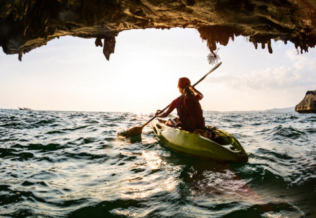 Girl canoeing through a cave in the ocean