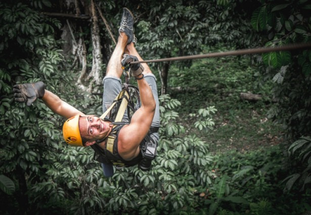 a man enjoying a zip line through the trees
