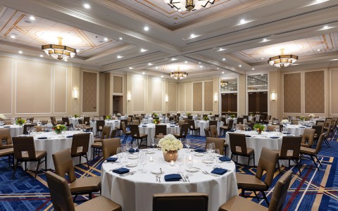 large round tables with white cloth and blue chairs 