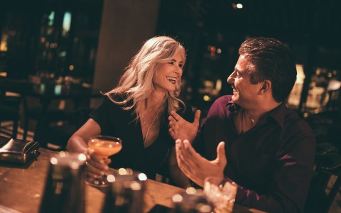couple laughing and smiling, woman is holding a cocktail