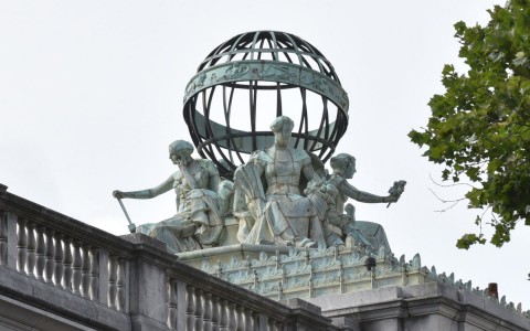 Exterior image showing three women sculpture and a world on a top of a building 