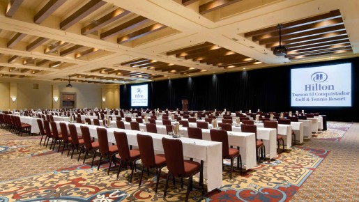 large event space with rows of chairs and tables and two screens in front