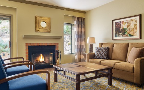 living rom area with a couch, coffee table, two chairs and a fireplace