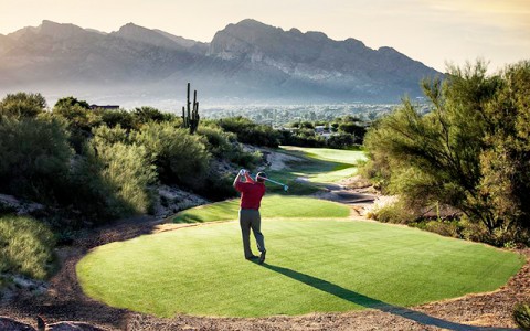 man playing golf with mountain view