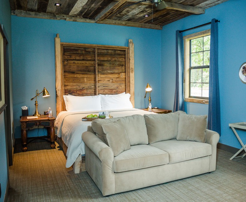 view of queen bed with wooden frame and pull out couch in a blue room