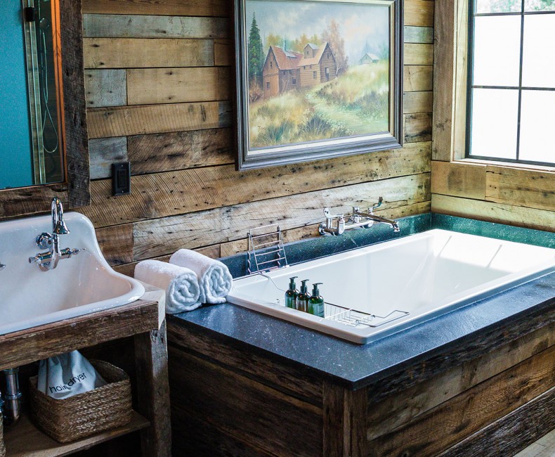 bathroom with a large wood bathtub by a window and double sink