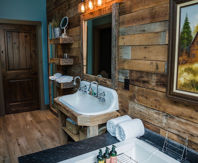 view of wooden bathroom with sink bathtub and painting of a cabin