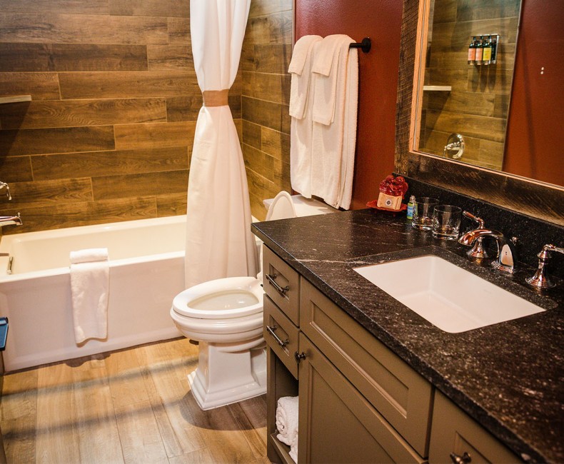 view of red bathroom with tub and black countertop sink with storage