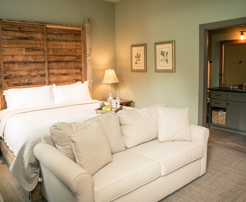 view of queen bed with wooden frame and a pull out couch in front