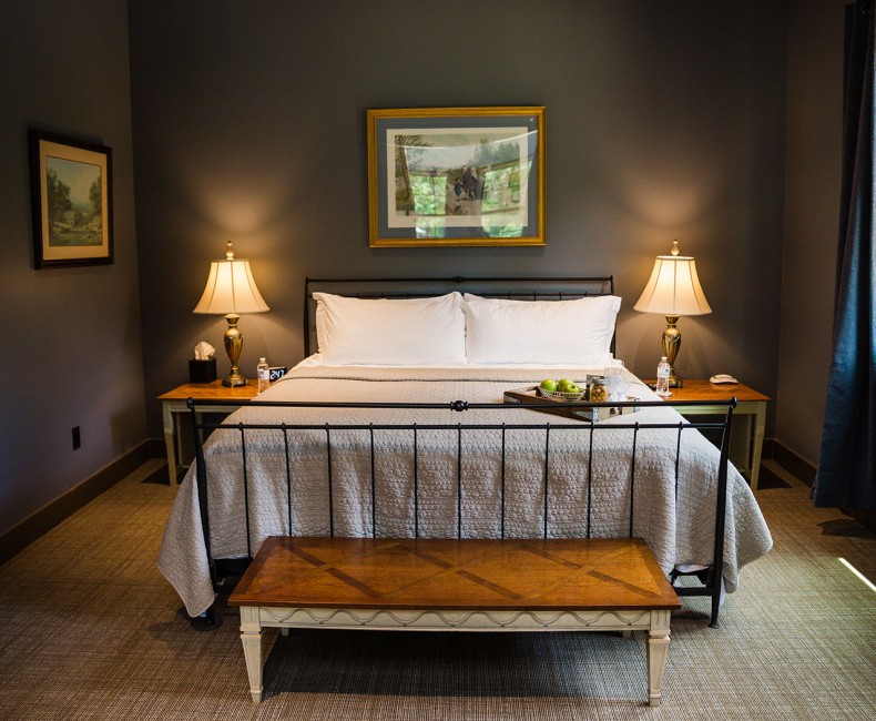 view of queen size bedroom with night stands on either side and paintings