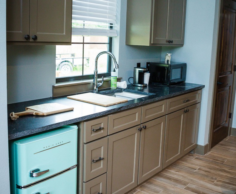 kitchenette with blue mini fridge and dark cabinets
