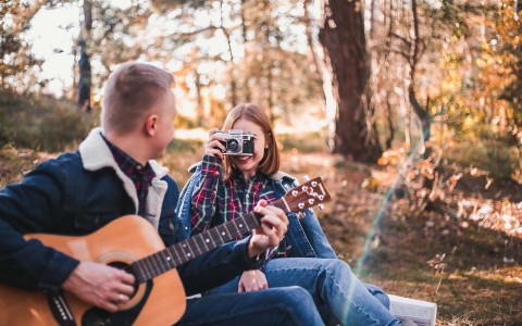 woman taking pictures of a man playing guitar 