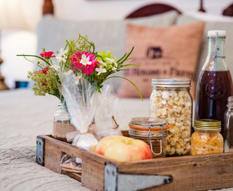 wooden tray with assorted food in it on a bed