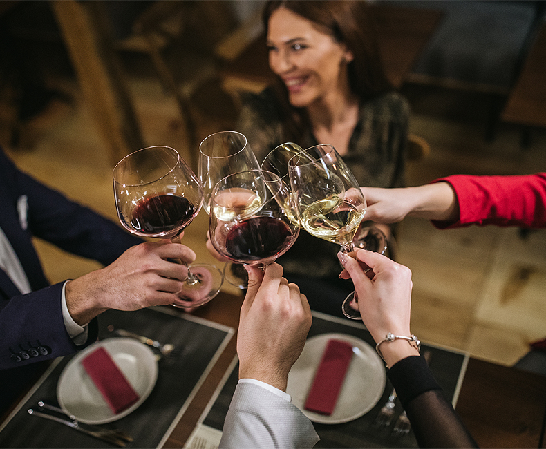 five people toasting with wine over a dinner table