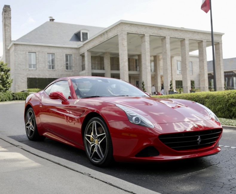 red ferrari in front of a large white brick home