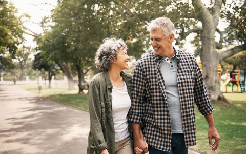 a smiling man and woman walking in a park during the day