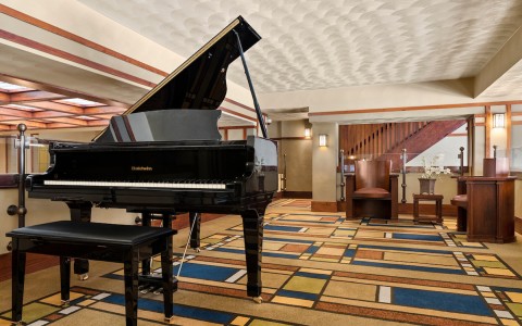 a piano in the lobby with a chair and a square rug 