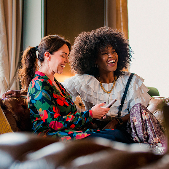 two smiling friends sitting in a couch