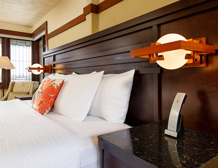 closeup of a bed with a solid wood headboard and soft lighting