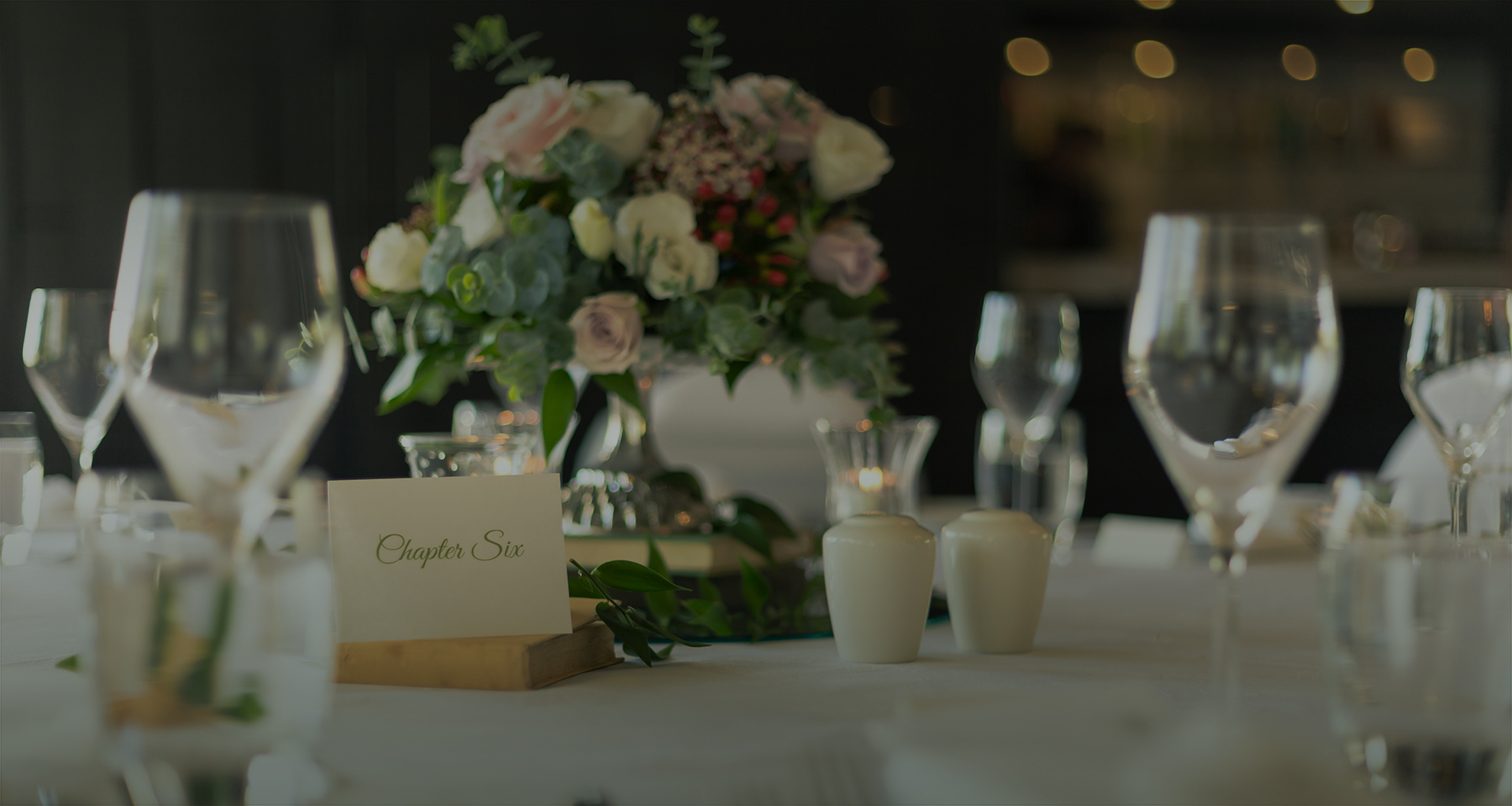 close up of a table set up for dinner with stemmed glasses and a floral centerpiece