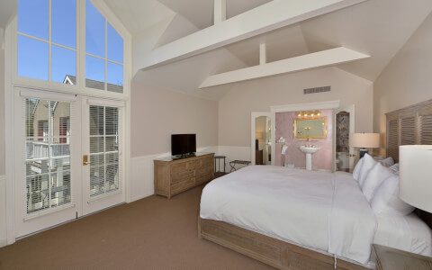 hotel bedroom with high arch ceilings and wide window with view