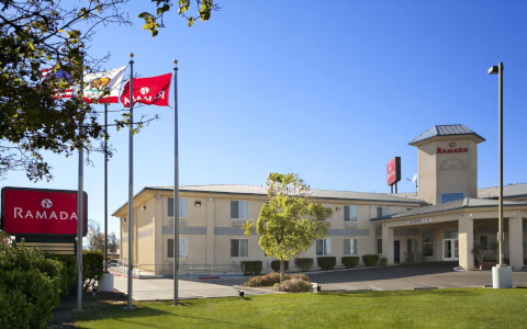 hotel entrance with three flag poles and green landscape