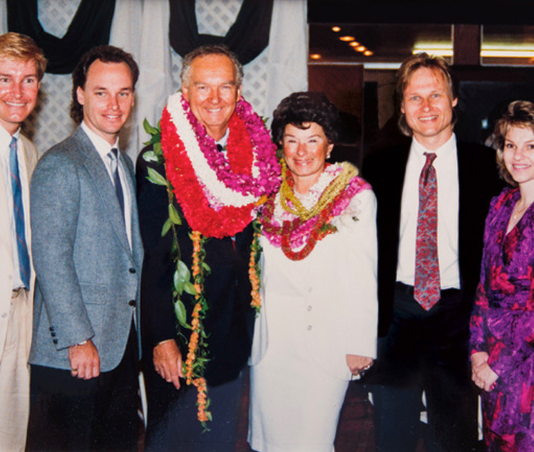 Group photo of Hogan Family smiling and wearing tropical necklaces