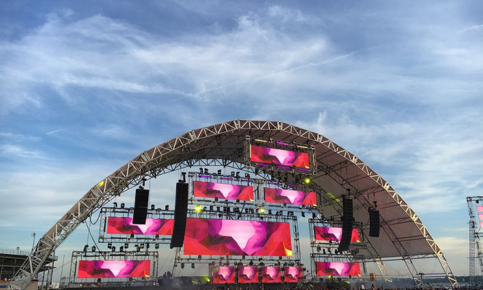 Outdoor Concert with arched stage blue sky and fans in the crowd